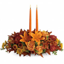 Orange floral centerpiece with two taper candles