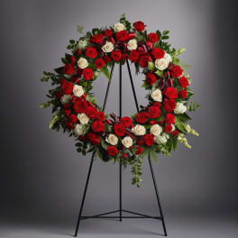 Circular wreath of red and white roses on a black stand