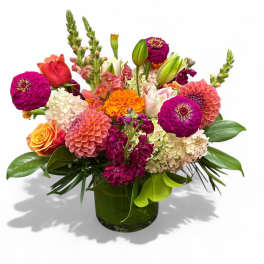 Colorful mixed bouquet in a green glass vase with zinnias and roses