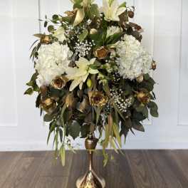 White floral arrangement with gold roses in a tall gold vase