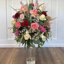 Mixed roses and filler flowers in a clear glass vase