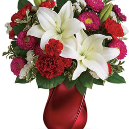 Bouquet of white lilies, red carnations, and pink mums in a red vase
