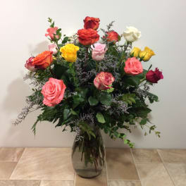 Mixed roses in a glass vase with purple filler flowers
