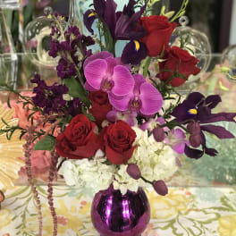 Mixed bouquet of red roses, purple orchids, and white hydrangea in a purple vase