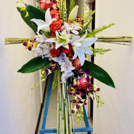Tall floral standing spray with red roses, white lilies, and orchids on bamboo