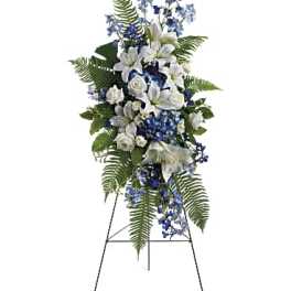 Standing floral spray with white lilies and blue flowers on an easel