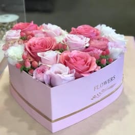 Pink and white roses arranged in a heart-shaped box