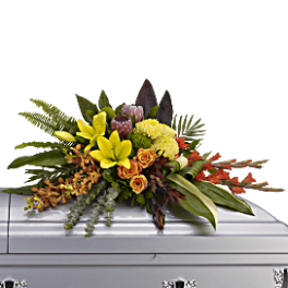 Bright mixed floral spray on a white casket