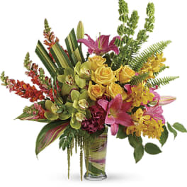 Tropical bouquet with pink lilies, yellow roses, and orchids in a glass vase