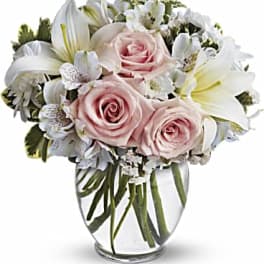 Pink roses and white lilies arranged in a clear glass vase