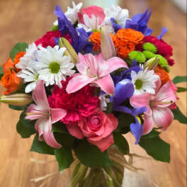Mixed bouquet of pink, purple, orange, and white flowers in a glass vase