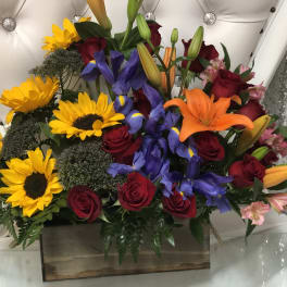 Mixed bouquet with sunflowers, roses, lilies, and irises in a wooden box