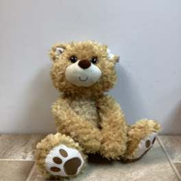 Plush teddy bear sitting on a tiled floor