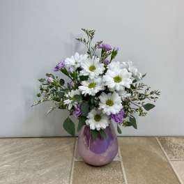 White daisies and purple blooms in a purple glass vase
