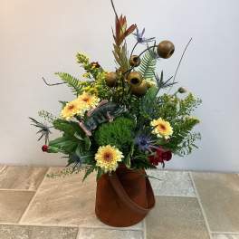 Mixed floral arrangement in a brown container with a fish decoration