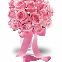 Pink rose bouquet in a clear vase with ribbon and pearl accents