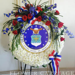 Circular floral wreath with red roses, white flowers, and blue accents around an Air Force emblem