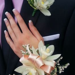 White floral corsage and boutonniere on a dark suit
