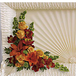 Orange and red floral spray on a white casket