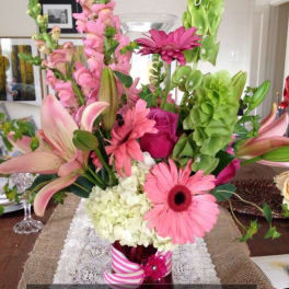 Pink and green floral arrangement in a vase with lilies and gerbera daisies