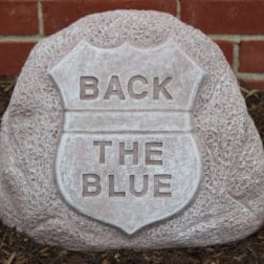 A stone sign shaped like a police badge with the words "BACK THE BLUE."