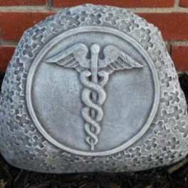 Gray memorial stone with a caduceus emblem in front of a brick wall