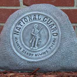 Gray memorial stone with a National Guard emblem against a brick wall
