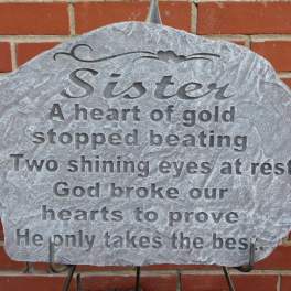 Memorial stone plaque with engraved text on a brick wall