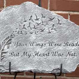 Engraved memorial stone with birds and a feather design