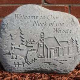 Engraved stone sign with a deer and cabin scene
