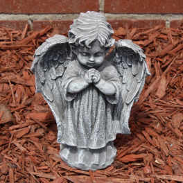 Gray angel garden statue with folded hands on red mulch