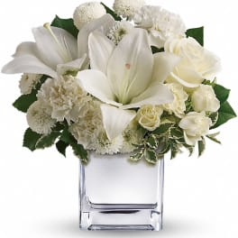 White lilies and roses arranged in a clear glass vase