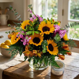 Bouquet of sunflowers and pink flowers in a clear glass vase