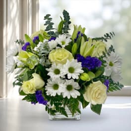 White daisies and pale yellow roses in a clear glass vase
