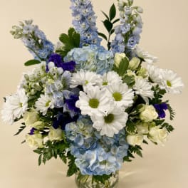 Blue and white floral arrangement in a clear glass vase