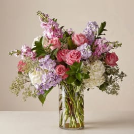 Pink and lavender roses with white blooms in a clear glass vase