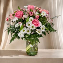 Pink roses and white daisies arranged in a glass vase
