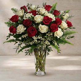 Red and white roses arranged in a clear glass vase.