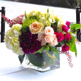 Mixed bouquet of roses, hydrangeas, and dahlias in a clear glass vase