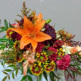 Bouquet with orange lily and mixed flowers in a woven handle wrap