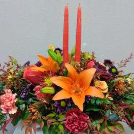 Bright floral arrangement with orange lilies and two red candles