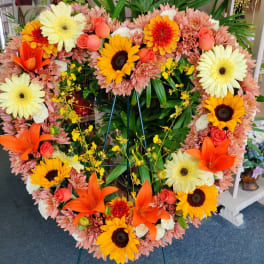 Heart-shaped floral wreath with sunflowers, lilies, roses, and gerbera daisies