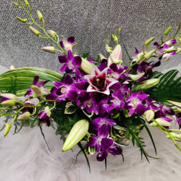 Purple orchid arrangement with white lilies and green foliage