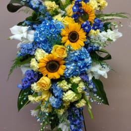 Tall standing floral spray with sunflowers, blue hydrangeas, and white blooms