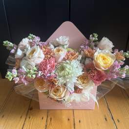 Pastel bouquet of roses, chrysanthemums, and carnations in a pink box