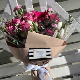 Pink and white mixed bouquet wrapped in blush paper with a white ribbon