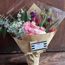 Bouquet of pink roses and purple flowers wrapped in newspaper-style paper