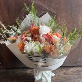 Bouquet of orange and white flowers wrapped in white paper with a ribbon