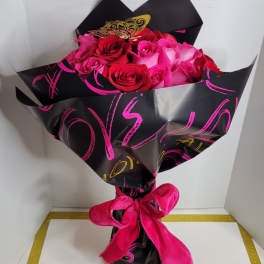 Bouquet of pink and red roses wrapped in black paper with a pink ribbon