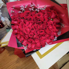 Large bouquet of red roses wrapped in pink and black paper